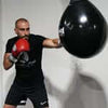 Boxer practicing with a speed bag, wearing red gloves and a black shirt, focused on training.